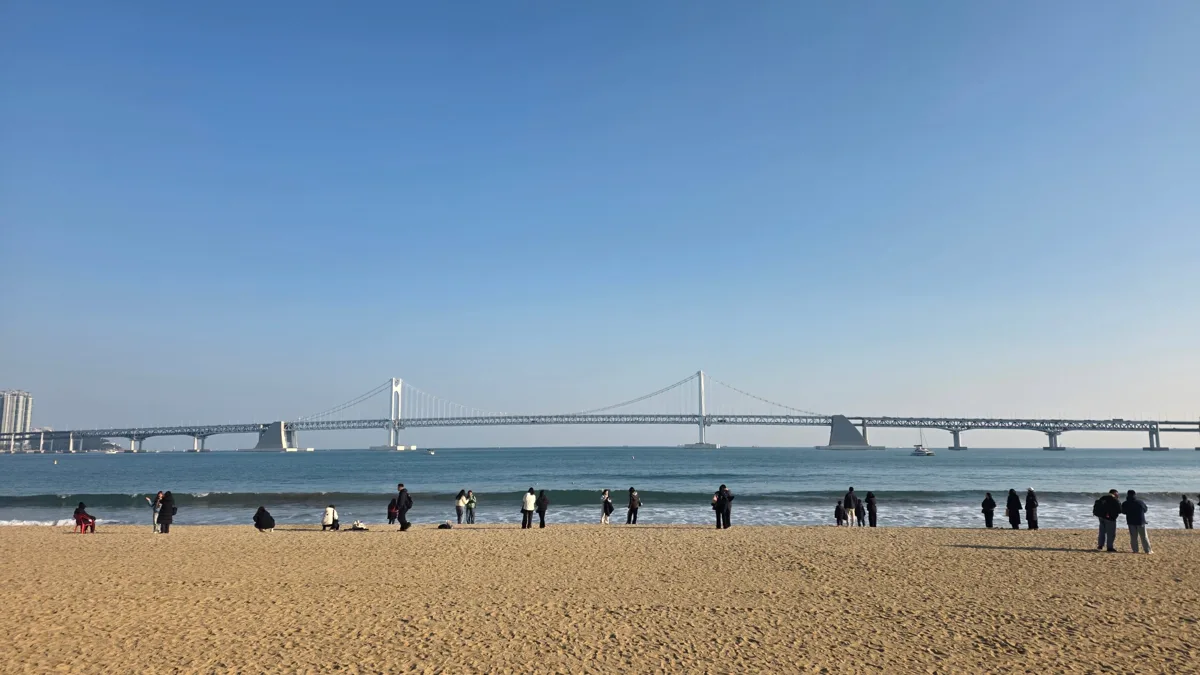 맑은 겨울 하늘 아래 광안리해수욕장 모래사장과 바다 건너 하얀 광안대교