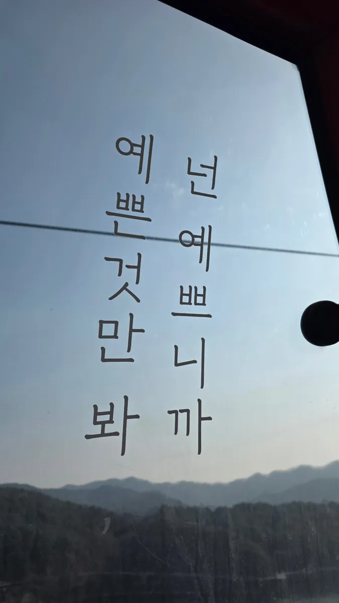 케이블카 창문에 적힌 문구 넌 예쁘니까 예쁜 것만 봐와 창밖의 산 능선